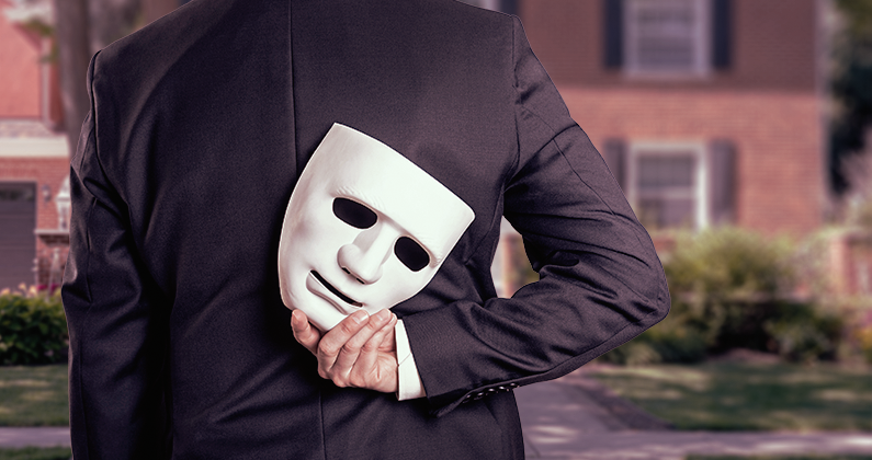 a man in a suit holding a mask behind his back